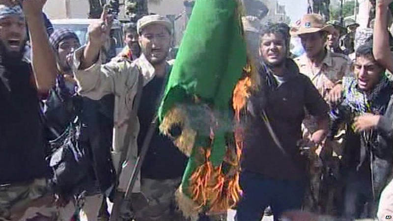 Үкіметке қарсы топ әскерлері Каддафи үкіметінің туын өртеп, "Ақиқат жасасын!" деп ұрандатуда